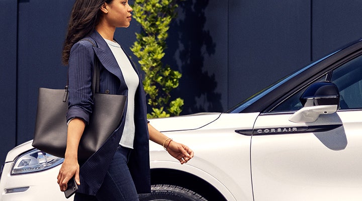 A woman approaches a 2024 Lincoln Corsair® SUV while holding a smartphone. | Ted Britt Chantilly Lincoln in Chantilly VA