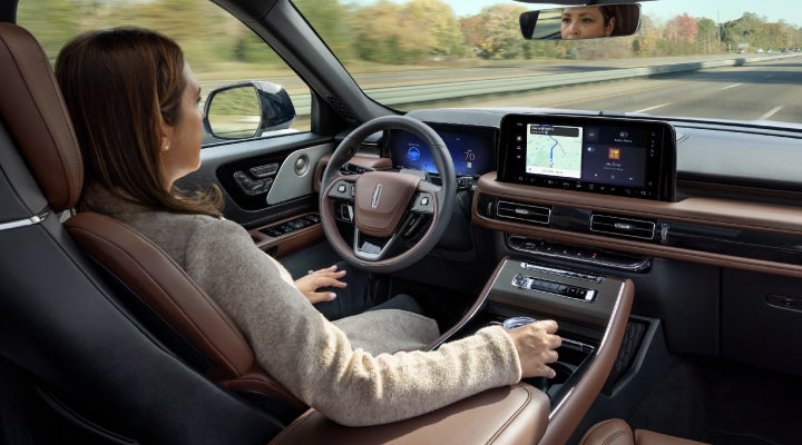 A 2026 Lincoln Aviator® SUV is being driven hands-free on a highway near a forest | Ted Britt Chantilly Lincoln in Chantilly VA