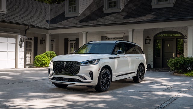 A white 2026 Lincoln Aviator® SUV is parked in the driveway of a luxury home. | Ted Britt Chantilly Lincoln in Chantilly VA