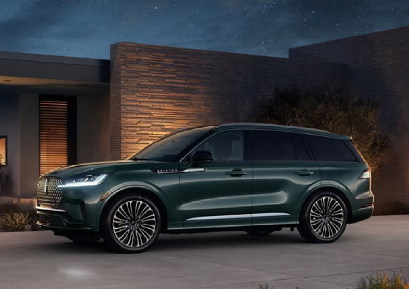 A green 2027 Lincoln Aviator® SUV is parked outside a contemporary home. | Ted Britt Chantilly Lincoln in Chantilly VA