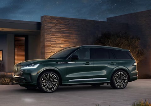 A green 2027 Lincoln Aviator® SUV is parked outside a contemporary home. | Ted Britt Chantilly Lincoln in Chantilly VA