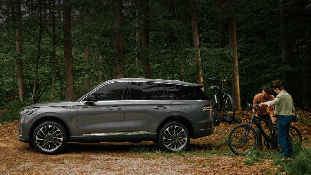 A father and son load e-bikes on a bike rack attached to a 2027 Lincoln Aviator® SUV. | Ted Britt Chantilly Lincoln in Chantilly VA