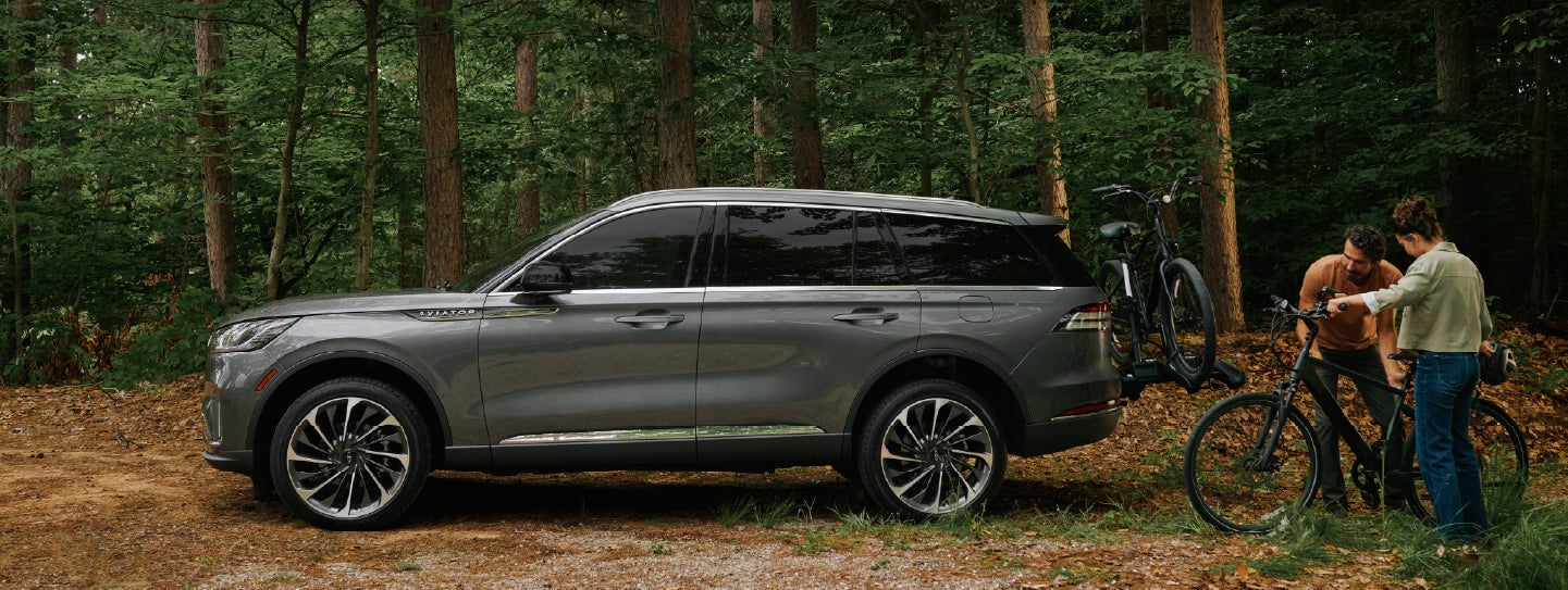 A father and son load e-bikes on a bike rack attached to a 2027 Lincoln Aviator® SUV. | Ted Britt Chantilly Lincoln in Chantilly VA